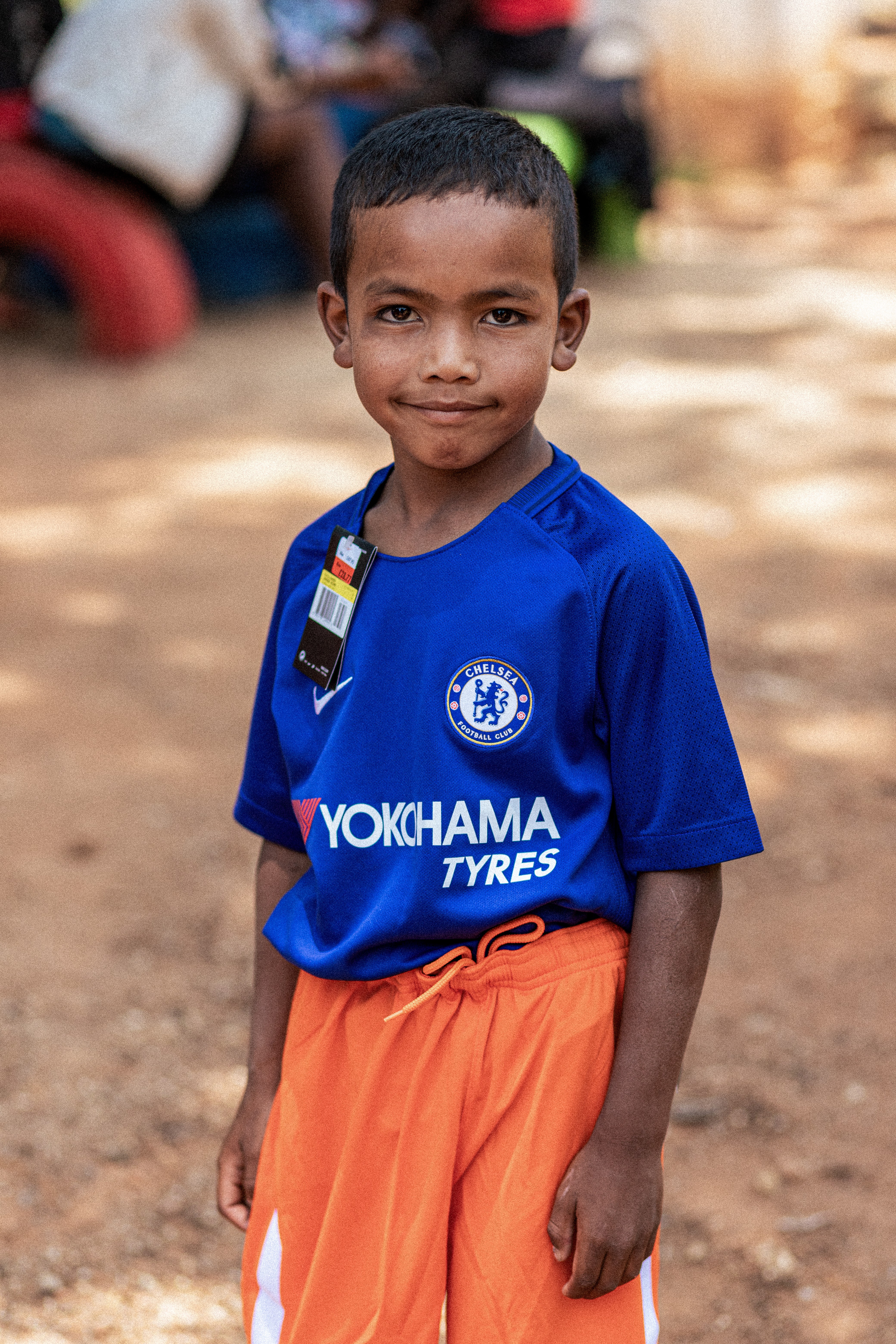 A boy wearing a blue Chelsea football shirt, smiling at the camera.